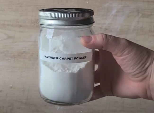 A person holding a jar of lavender carpet powder