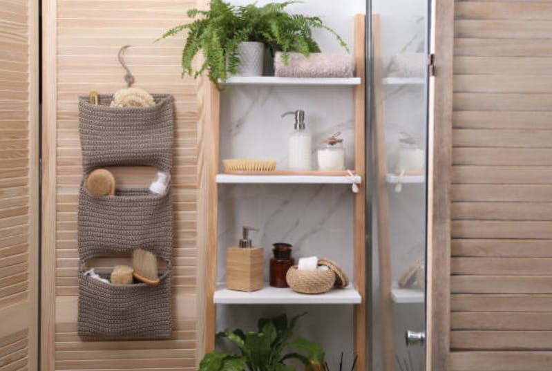 A wooden rack shelve for different bathroom necessities with a green plants in it