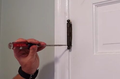 A person screwing the door's hinge