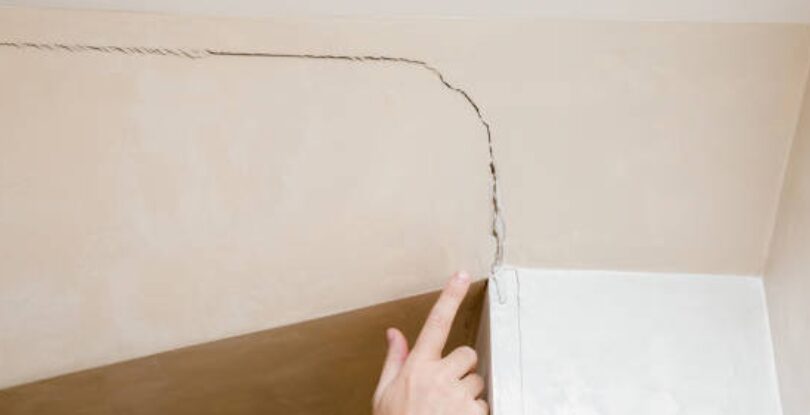 A person pointing at a ceiling crack