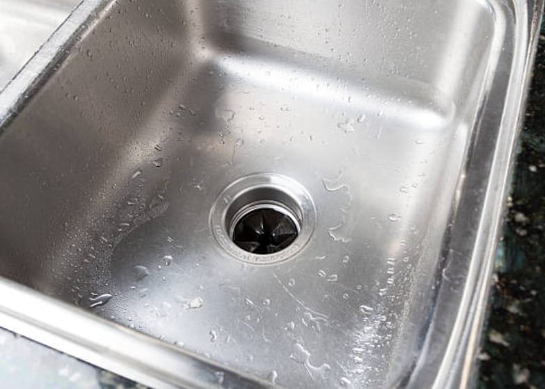 A stainless steel kitchen sink with water droplets on it