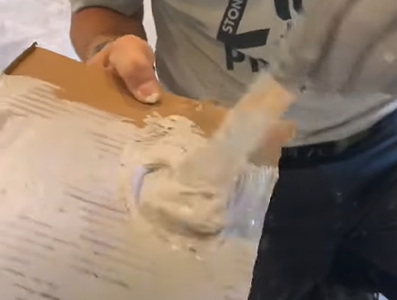 A person mixing the solution on the cardboard using popsicle