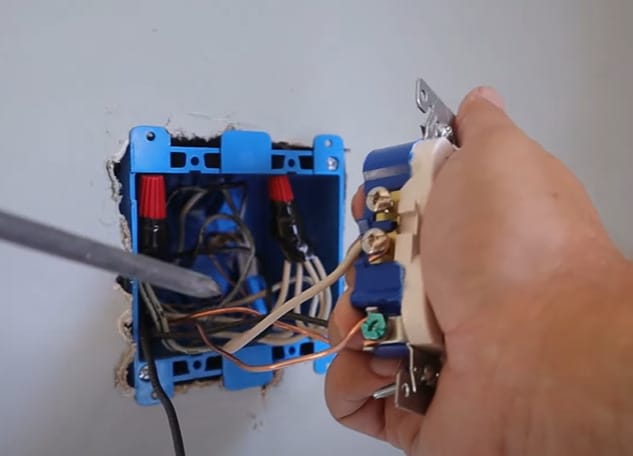 A person is wiring a light switch into an outlet box