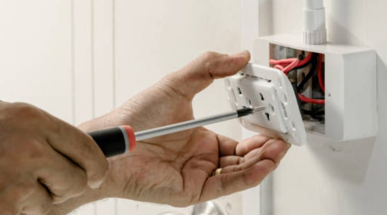 A man opening an outlet box with a screwdriver