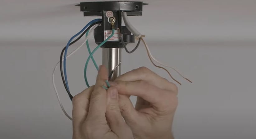 A person connecting the green wires of a ceiling fan light