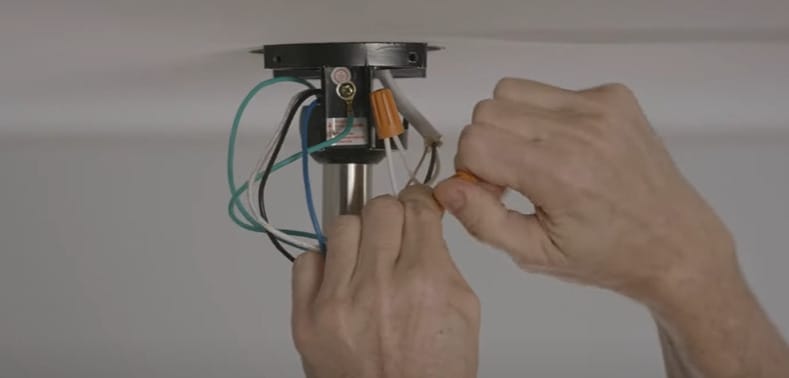 A person capping off the wires of a ceiling fan light