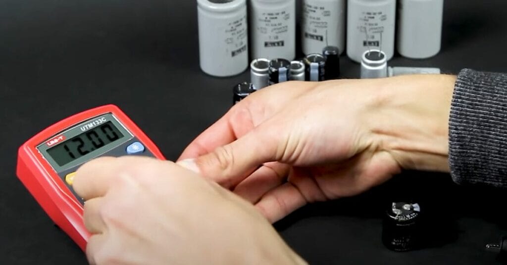 A person is setting the digital voltmeter to test batteries and capacitors