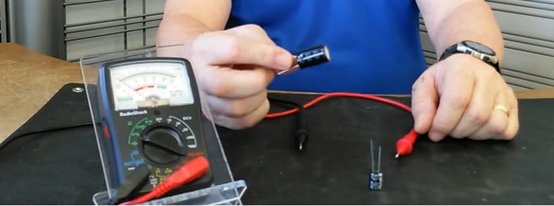 A man demonstrates how to test a capacitor using a multimeter
