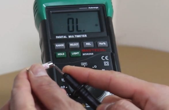 A person using a multimeter to test a fuse