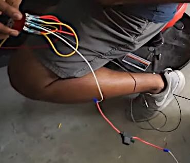 A man is working on a car with wires attached to it