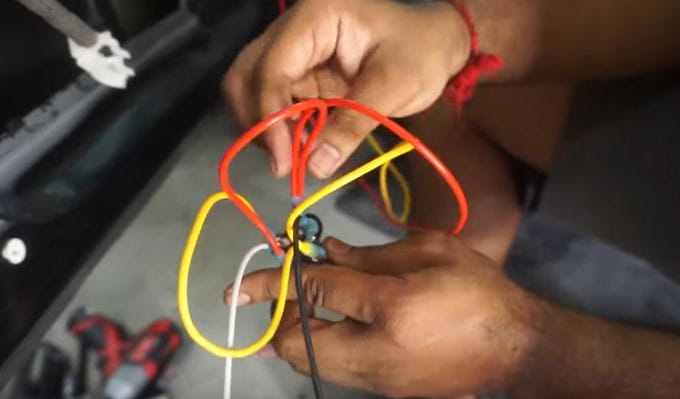 A man is working on the wiring of a car's toggle switch