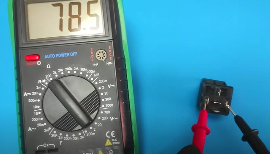 A person is testing the relay with a multimeter at a reading of 78.5