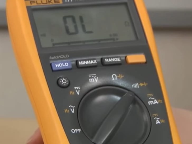 A person is holding a fluke multimeter to test electrical continuity
