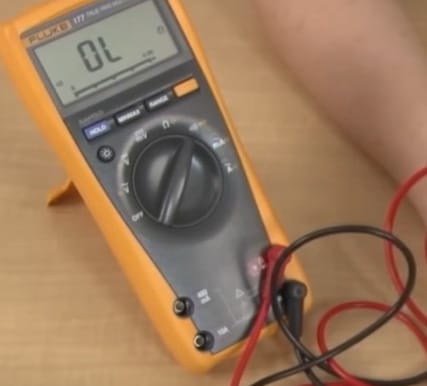 A person is using a multimeter on the table