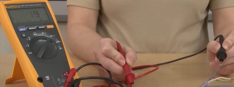 A person is using a multimeter to check the continuity symbol on a circuit board in a table