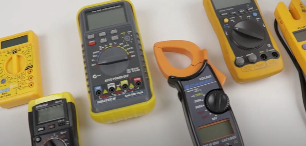 A group of different types of multimeters on the white table