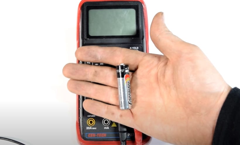 A battery is placed at a person's palm while a multimeter is at the back