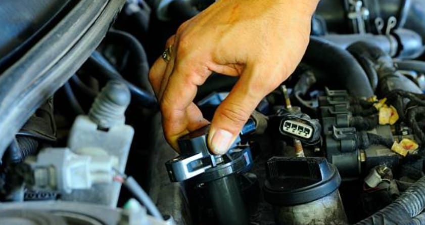 A person is checking the coil pack of a car