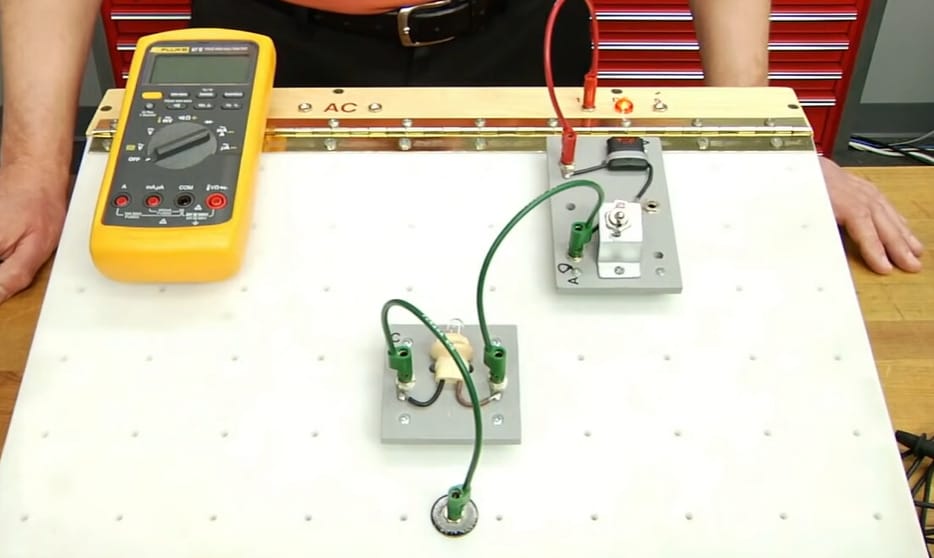 A person in front of the table with multimeter and circuit board