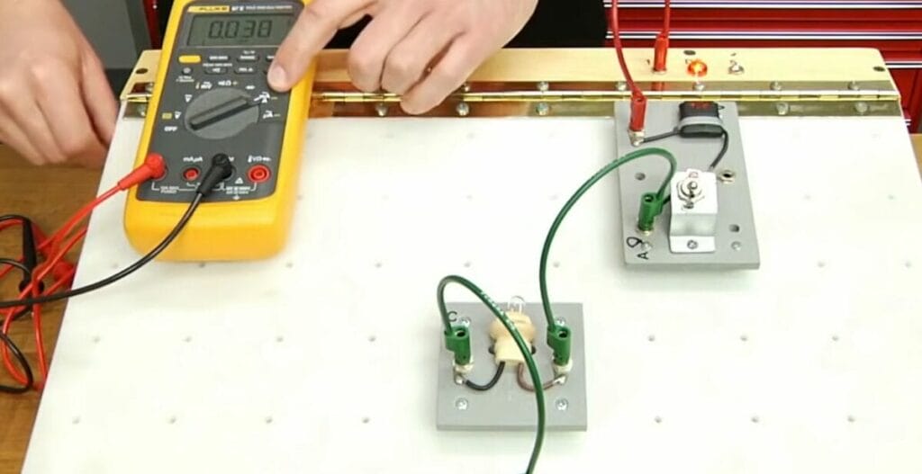 A person is setting the multimeter to test a circuit board