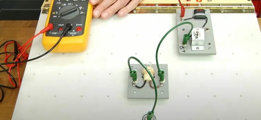 A person connecting the probe into the multimeter to test a circuit board