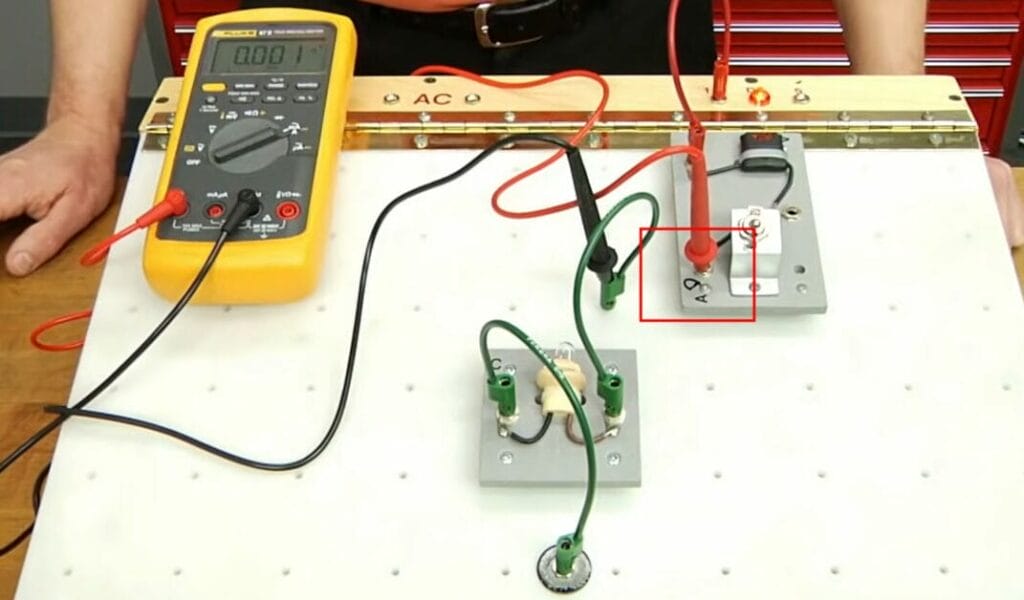 A person connecting the probe of the multimeter into the circuit board for testing