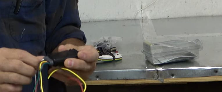A man is working a trailer light wire on a table