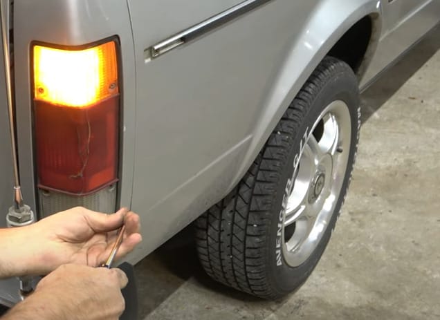A man is screwing back the cover of a the car's trailer light