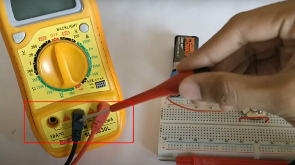A person is using a multimeter to check continuity in a circuit