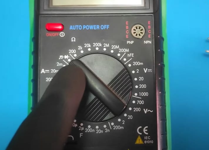 A person in black gloves setting the multimeter for testing