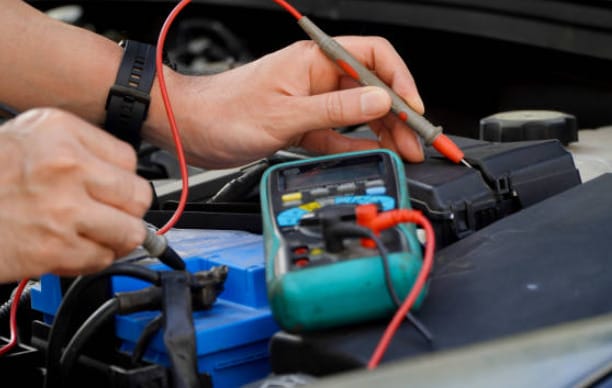 A man is using a multimeter to check the battery of a car