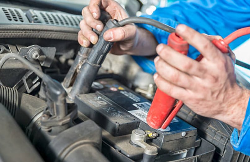 A man working on a car battery to determine if a bad starter can drain the battery to determine if a bad starter can drain the battery.