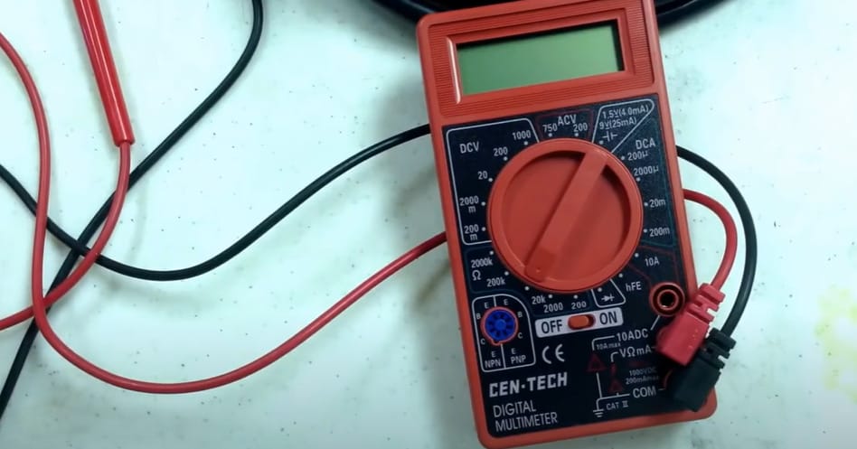 A red Cen Tech multimeter with wires connected to it