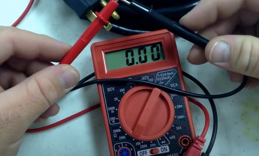 A person is using a Cen Tech multimeter to test a wire