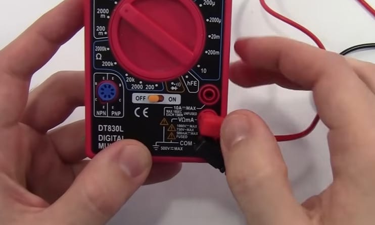 A person is holding a Centech multimeter