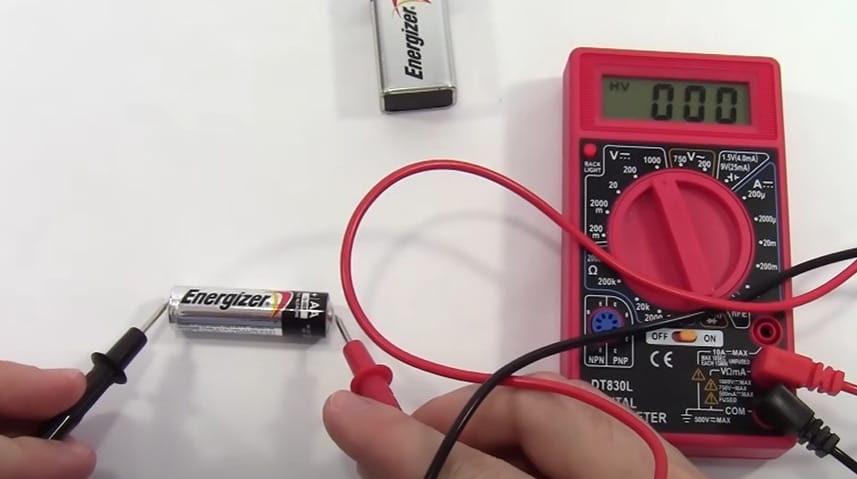 A person is using a Cen Tech multimeter to test a battery