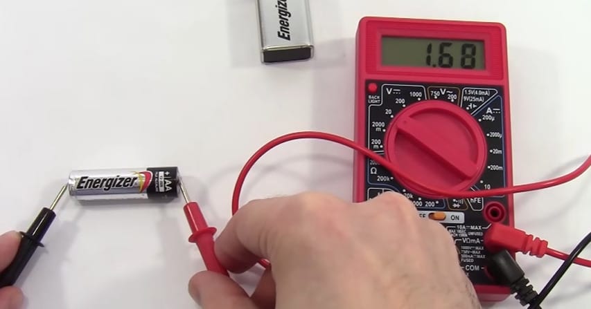 A person is using a Cen Tech multimeter to test a battery