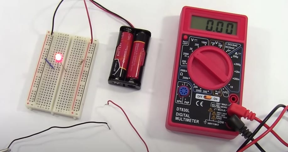 A Cen Tech multimeter is next to a battery and circuit board