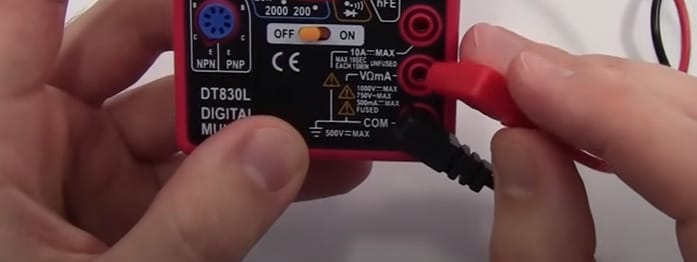 A person connecting the black and red probes to the multimeter