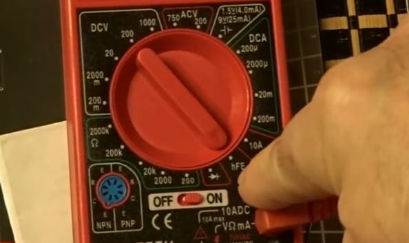 A person is holding a red Cen-Tech multimeter