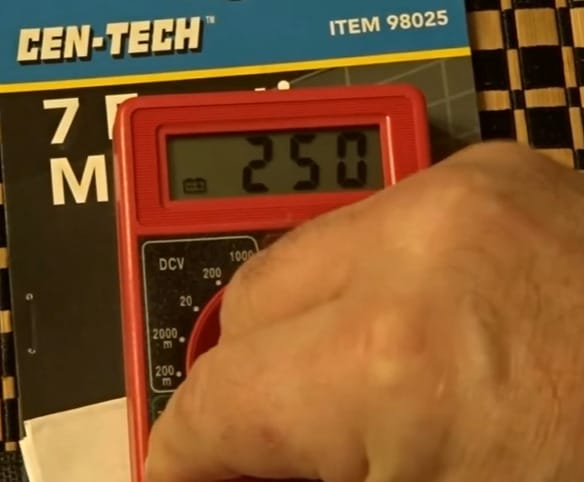 A person holding a Cen Tech multimeter on top of a package