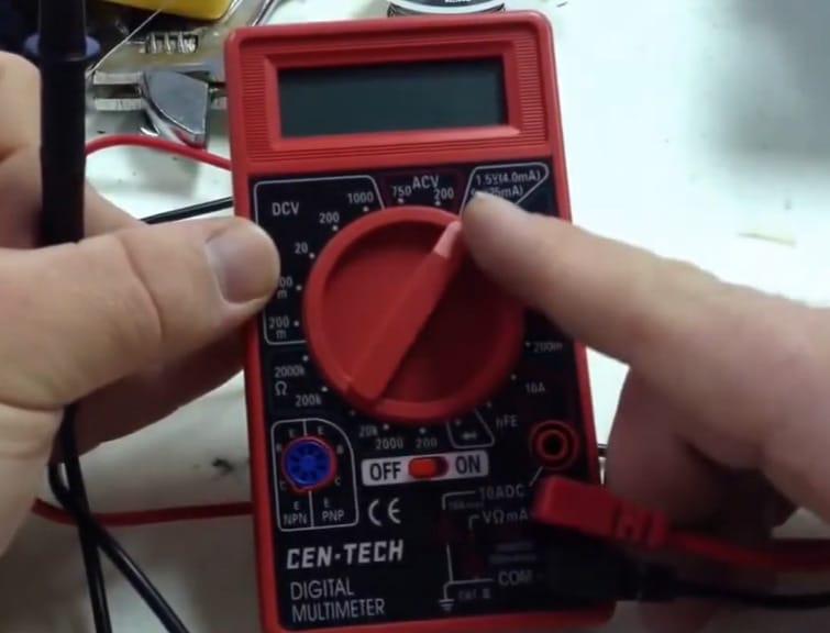 A person using a Cen Tech multimeter to test wires