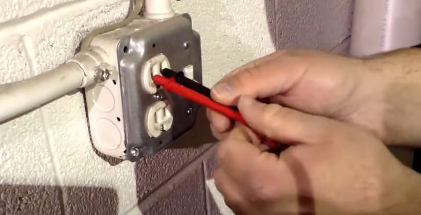 A man is testing wall outlet with multimeter