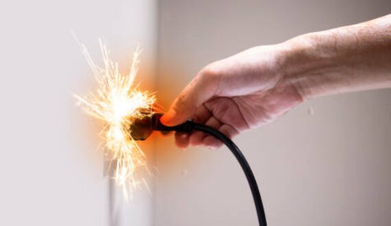 A person inserting plug wire in an outlet that causes fire spark