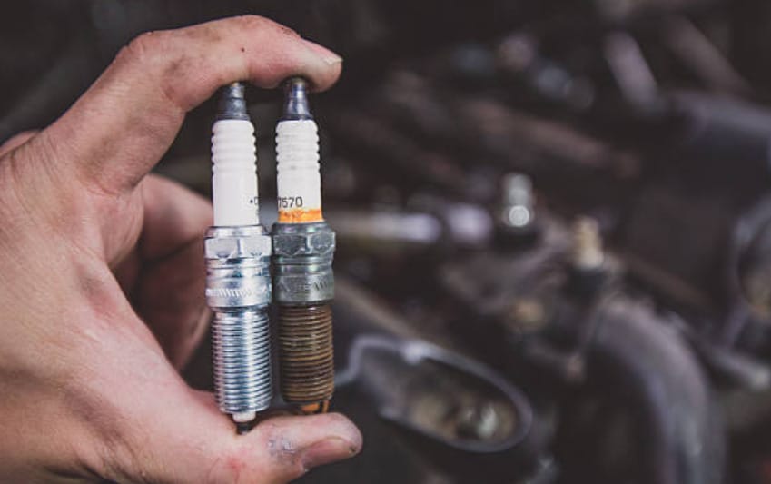 A man holding two spark plug of a car
