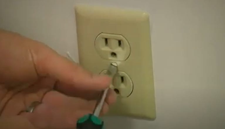 A person is using a screwdriver to open an outlet cover
