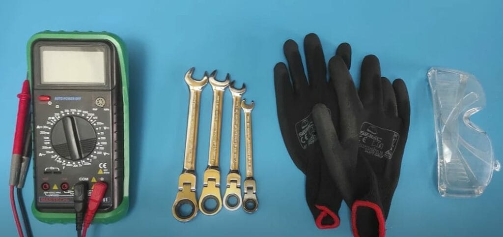 A multimeter, wrench of different sizes, black safety gloves, safety goggles on a blue background