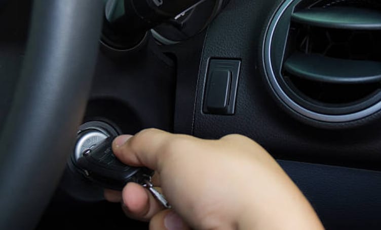 A person is inserting the key into the car key hole