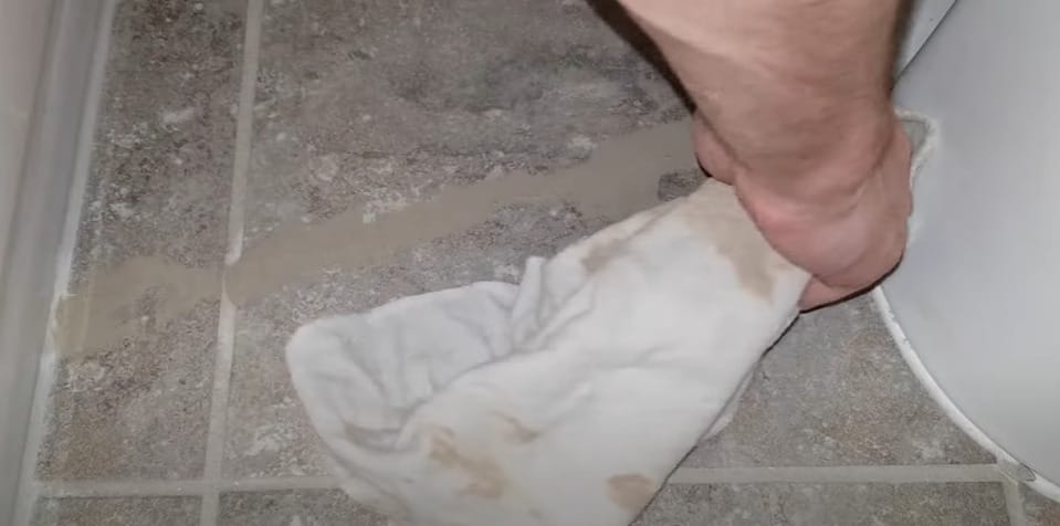 A person applying a urethane sealant using a towel