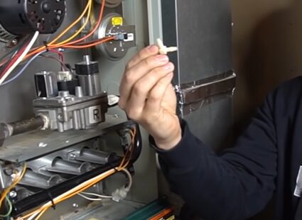 A man is testing a gas furnace's pressure switch